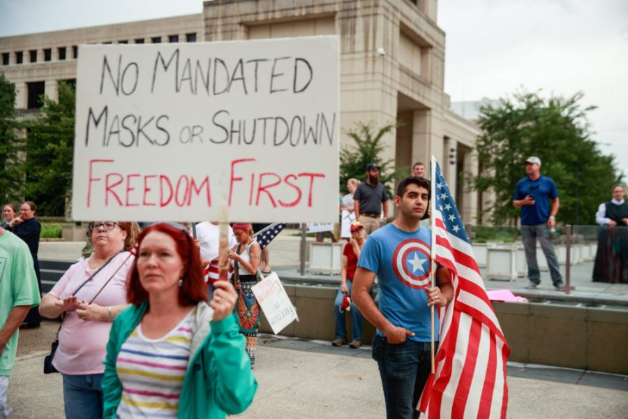 INDIANAPOLIS%2C+INDIANA%2C+UNITED+STATES+-+2020%2F07%2F19%3A+A+protester+holds+a+placard+saying+No+Mandated+Masks+or+Shutdown+Freedom+First+during+the+We+Will+Not+Comply+anti+mask+rally.%0APeople+protest+against+both+the+Indianapolis+mayor+Joe+Hogsetts+mask+order+and+Indiana+governor+Eric+Holcombs+extension+of+the+state+shutdown.%0AThe+U.S.+Department+of+Health+recorded+a+total+of+3%2C898%2C550+infections%2C+143%2C289+death+and+1%2C802%2C338+recovered+since+the+beginning+of+the+Coronavirus+%28Covid-19%29+outbreak.+%28Photo+by+Jeremy+Hogan%2FSOPA+Images%2FLightRocket+via+Getty+Images%29